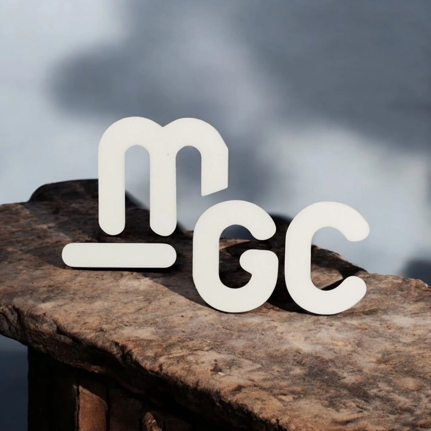 Logo MGC blanco sobre una superficie de piedra al aire libre